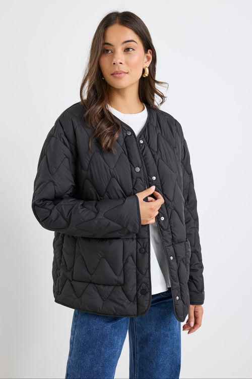 Woman wearing a black quilted jacket on a white background