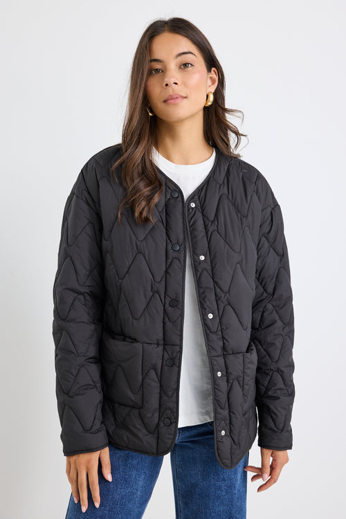 Woman wearing a black quilted jacket on a white background