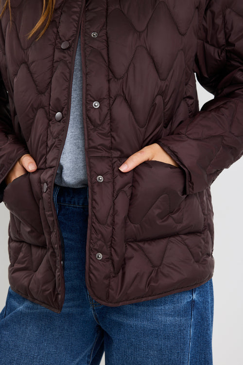 Person wearing a brown quilted jacket on a white background