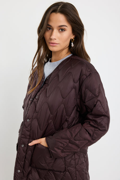 Woman wearing a dark quilted jacket on a white background