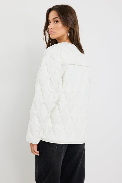 Woman wearing a white quilted jacket on a plain background