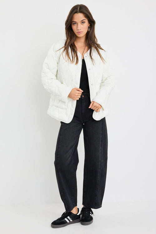 Woman wearing a white jacket, black top, and pants on a white background