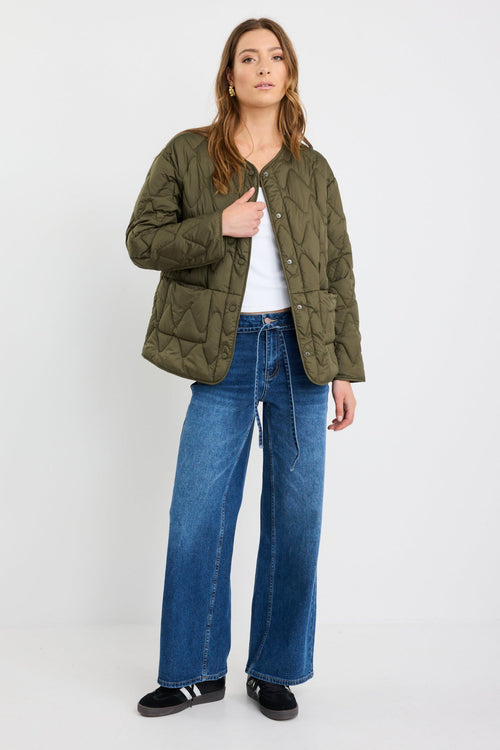 Woman wearing a green jacket and blue jeans on a white background