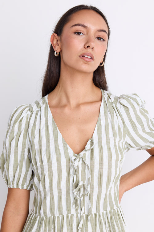 Model wearing a khaki striped puff sleeve mini dress with a V-neckline, puff sleeves, and a tie detail at the front.
