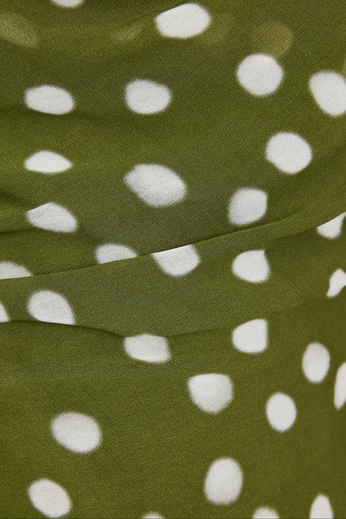 Close-up of olive green fabric with a white polka dot pattern.
