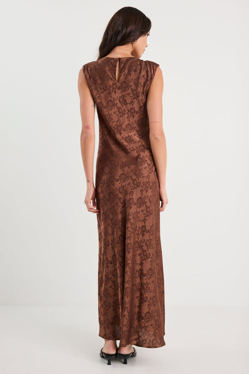 Woman wearing a brown patterned dress on a white background