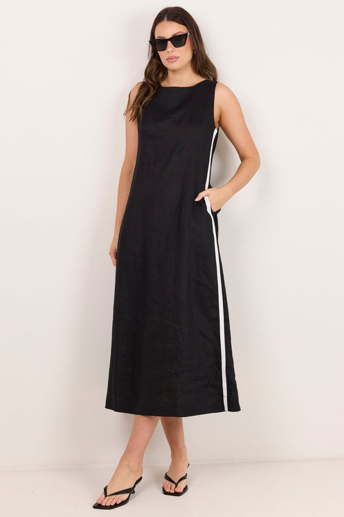 A woman modeling a sleeveless black midi dress with white side stripes, styled with black sunglasses and black sandals against a plain off-white studio background.