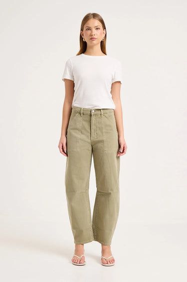 A woman modeling a pair of high-waisted, wide-leg olive green trousers, styled with a white t-shirt and light pink sandals against a plain white studio background.