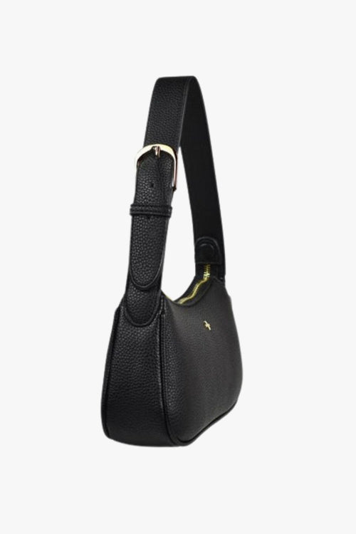 A small black vegan leather shoulder bag with a softly structured silhouette, featuring a grainy pebble texture, gold zip closure, and an adjustable black strap. The front is finished with a subtle gold cross logo, adding a touch of elegance.
