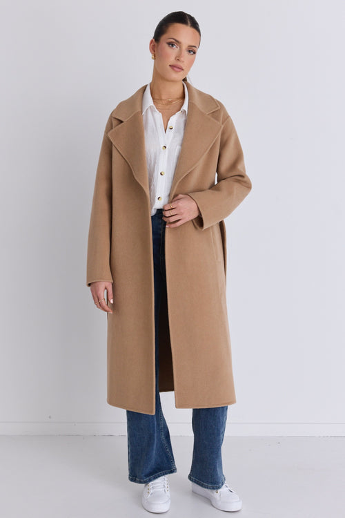 Model wears a brown beige coat with blue jeans