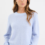 Woman wearing a light blue sweater against a white background