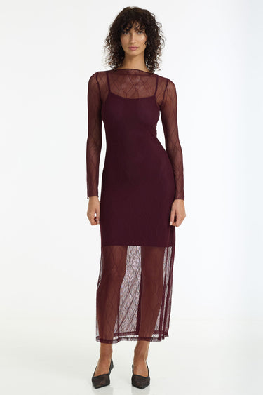 Woman wearing a burgundy dress with sheer sleeves on a white background