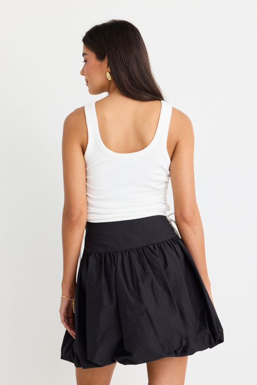 model wearing white crop tank top and black mini skirt