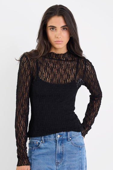 Woman wearing a black lace top and blue jeans on a white background