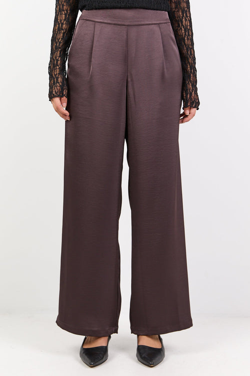 Woman wearing a black top and brown pants on a white background