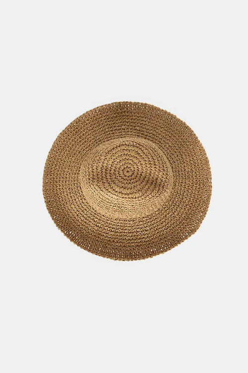 A round woven straw hat photographed from directly above on a light gray background.