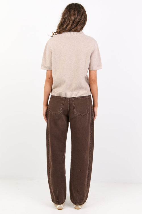 Person wearing a beige sweater and brown pants on a white background