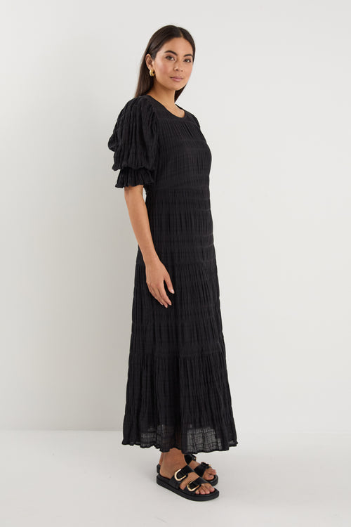 model wears a black maxi dress with black sandals