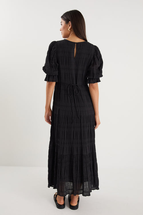 model wears a black maxi dress with black sandals