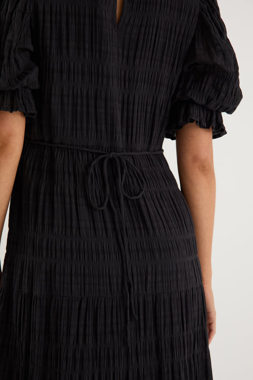 model wears a black maxi dress with black sandals