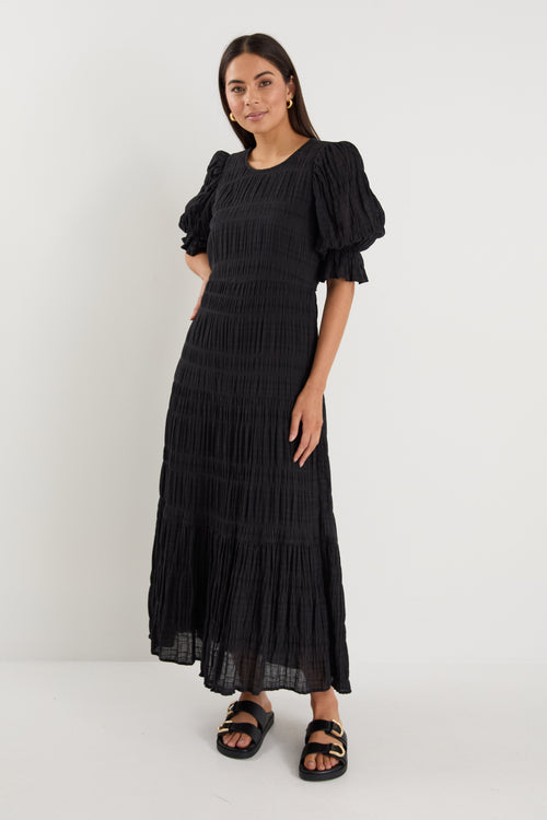 model wears a black maxi dress with black sandals