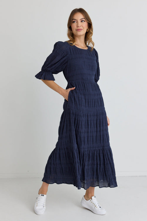 model wears long avy blue maxi dress with sleeves and white sneakers