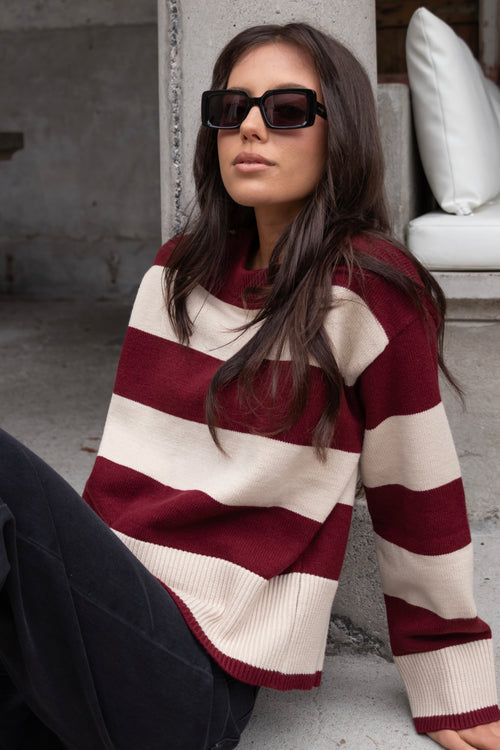 Model wears a burgundy and beige long sleeve stripe jumper