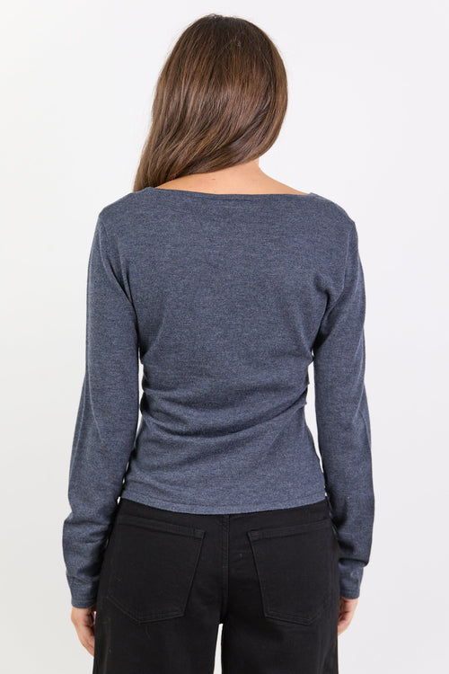 Person wearing a charcoal long-sleeve shirt and black pants on a white background