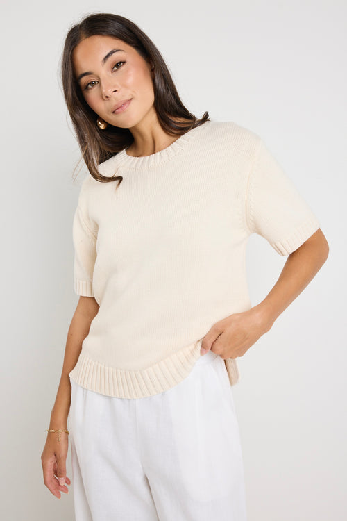 Mode wears a cream knit rounded neckline top with white linen pants