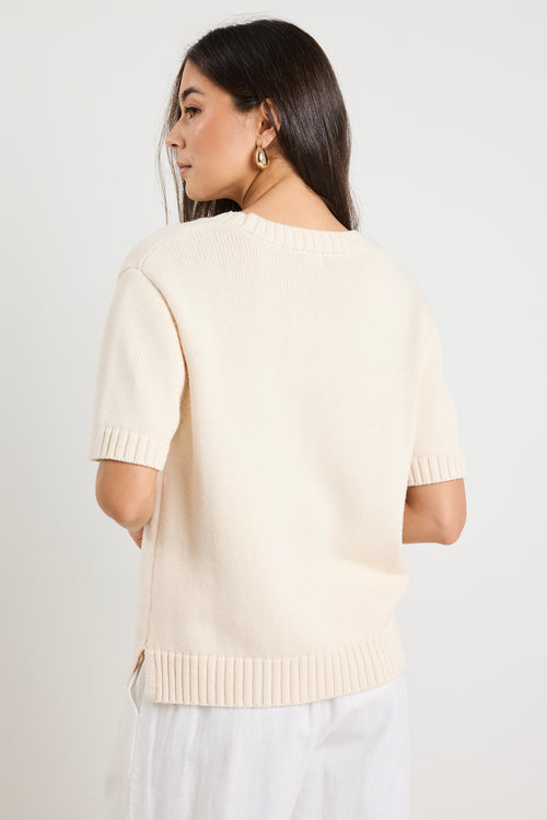 Mode wears a cream knit rounded neckline top with white linen pants