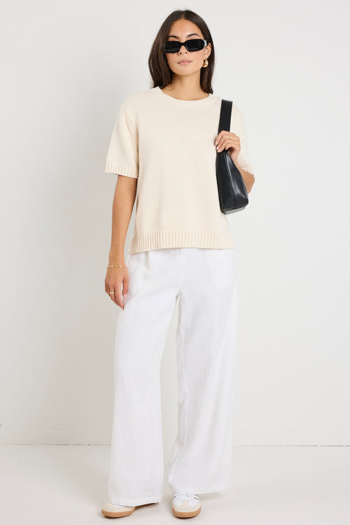 Mode wears a cream knit rounded neckline top with white linen pants