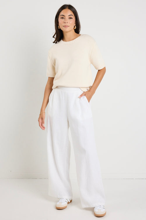 Mode wears a cream knit rounded neckline top with white linen pants