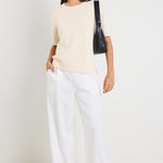 Mode wears a cream knit rounded neckline top with white linen pants