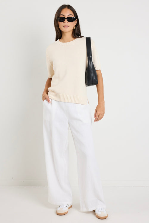 Mode wears a cream knit rounded neckline top with white linen pants