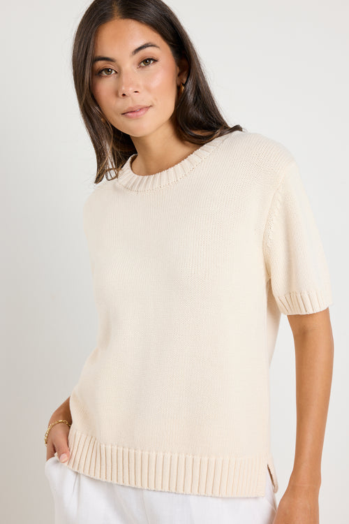 Mode wears a cream knit rounded neckline top with white linen pants