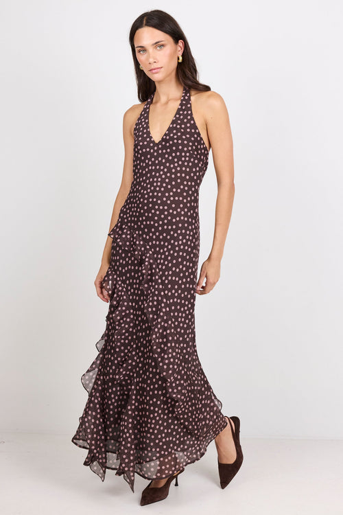 Woman wearing a brown halter maxi dress with pink polka dots on a white background.
