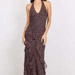 Woman wearing a brown halter maxi dress with pink polka dots on a white background.