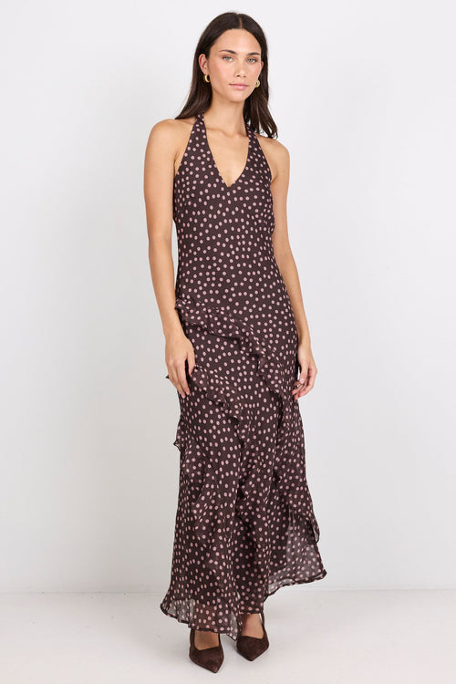 Woman wearing a brown halter maxi dress with pink polka dots on a white background.