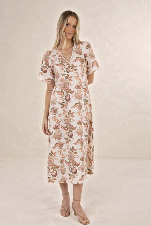 Woman wearing a floral dress against a plain background