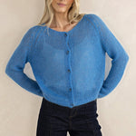 Woman wearing a blue knitted cardigan against a beige background