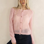 Woman wearing a pink knitted cardigan against a plain background