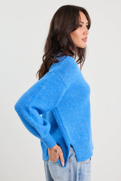 Woman wearing a blue sweater and light blue jeans on a white background