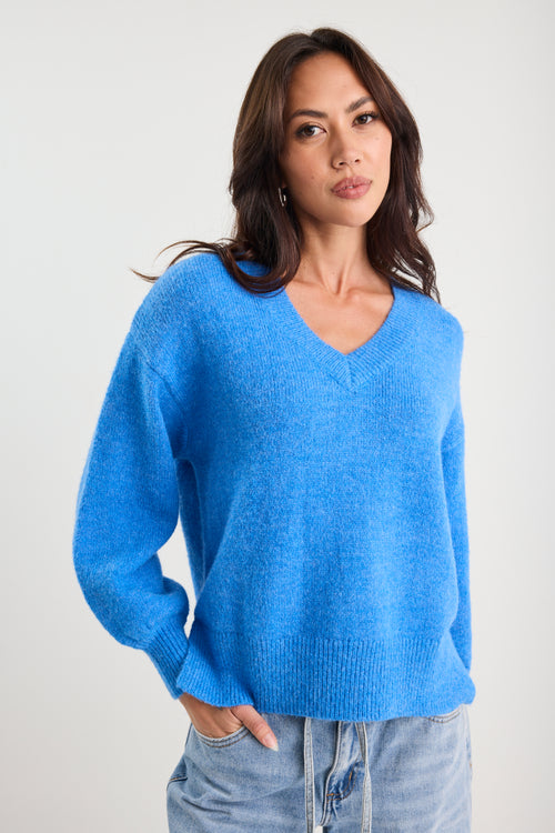 Woman wearing a blue sweater against a plain background