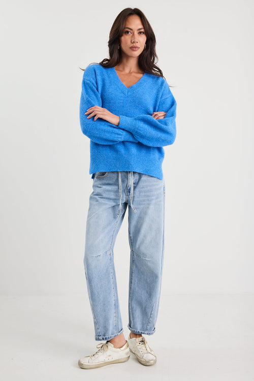 Woman wearing a blue sweater and light blue jeans on a white background