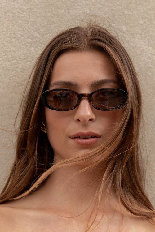Woman wearing sunglasses against a plain background