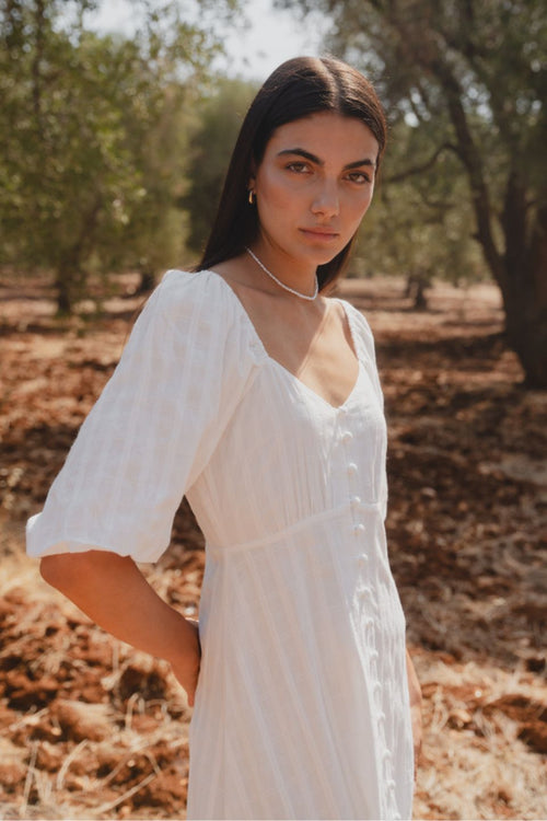 model wears a white midi dress