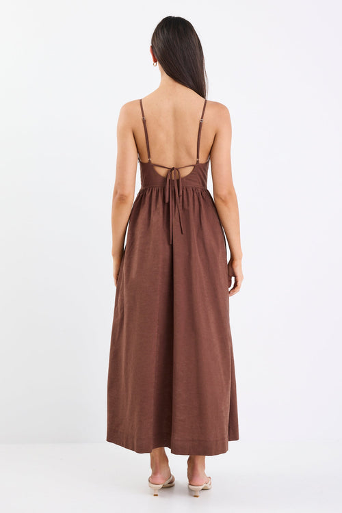 Woman wearing a brown dress with thin straps on a white background