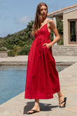Woman in a red dress standing by a pool with a scenic background