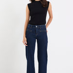 Woman wearing dark blue jeans and a black top on a white background