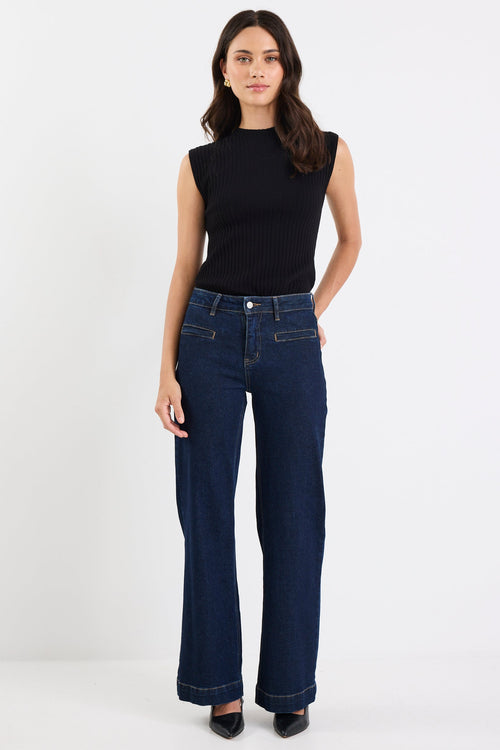 Woman wearing dark blue jeans and a black top on a white background